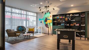 A modern room with a foosball table, comfortable seating, and a large window offering a view of the city.