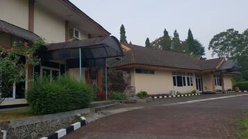 A building with a tiled roof, a covered entrance, and a paved driveway.