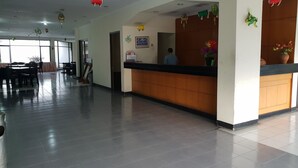A hotel reception area with a wooden counter, a receptionist, and a large window in the background. - Hotel Cisarua Indah (Cisarua)