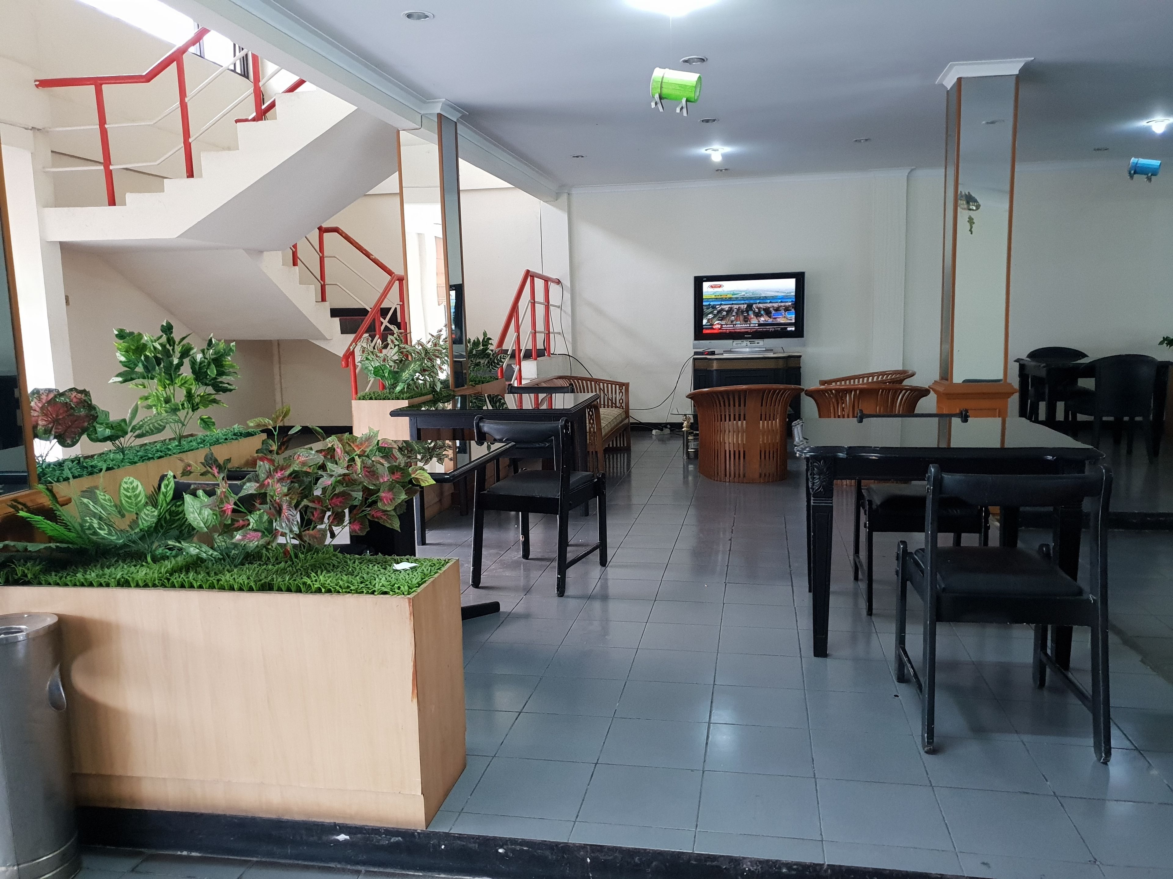 Un moderno vestíbulo de hotel con una escalera, zona de estar y una pantalla de televisión.