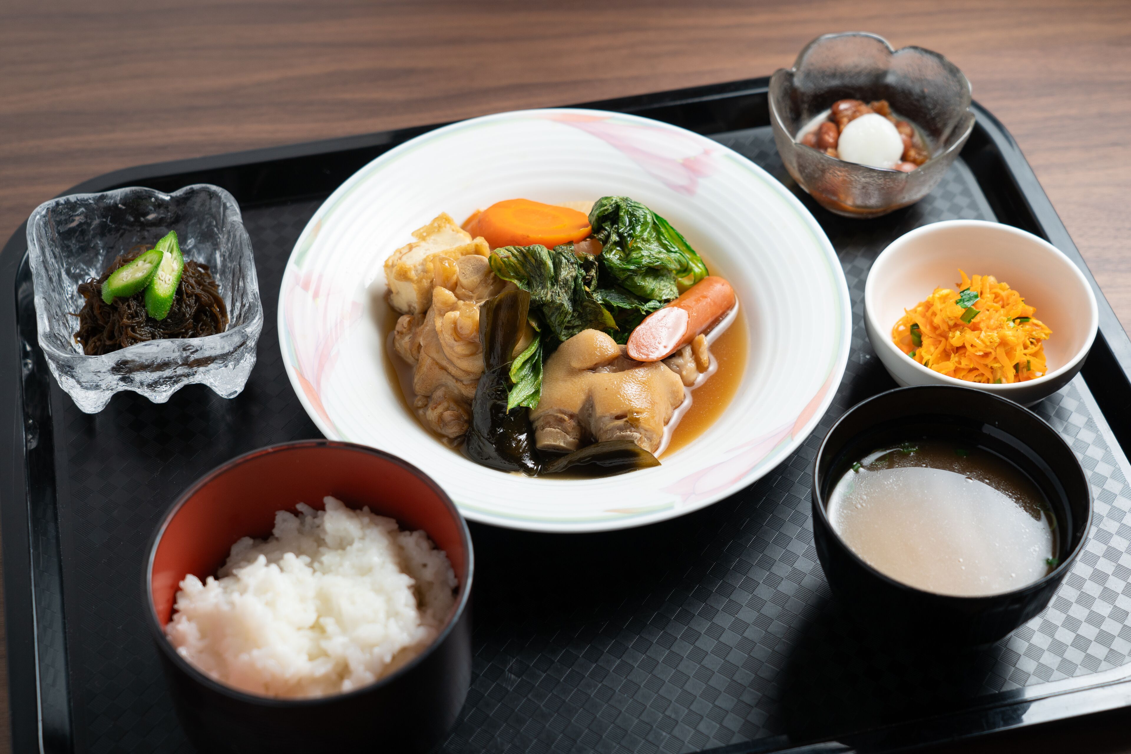 A tray with a bowl of soup, a bowl of rice, a bowl of pickled vegetables, a bowl of miso soup, and a small dish of sliced green onions.