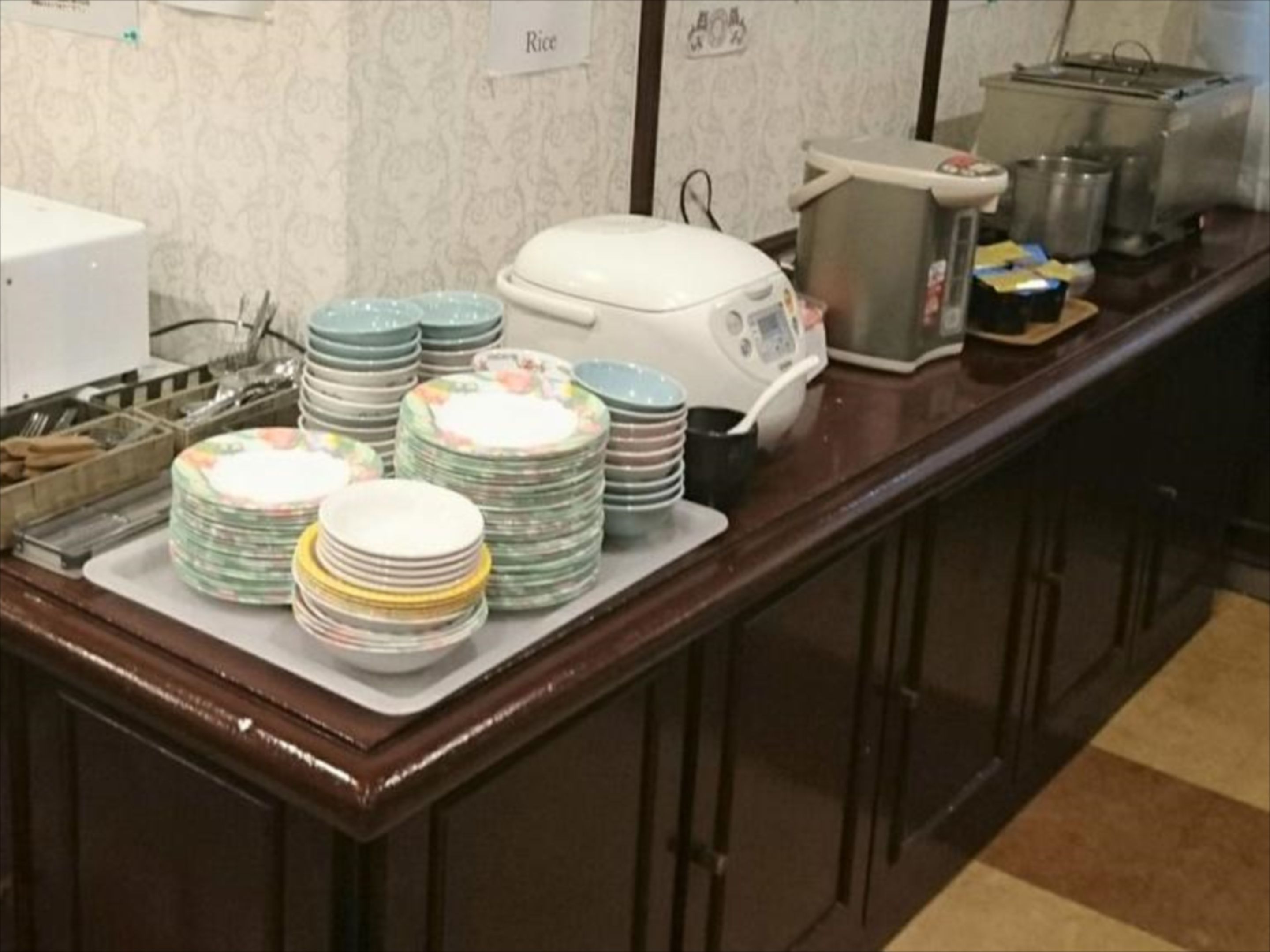A kitchen counter with stacks of plates and a rice cooker.