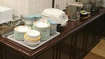 A kitchen counter with stacks of plates and a rice cooker.