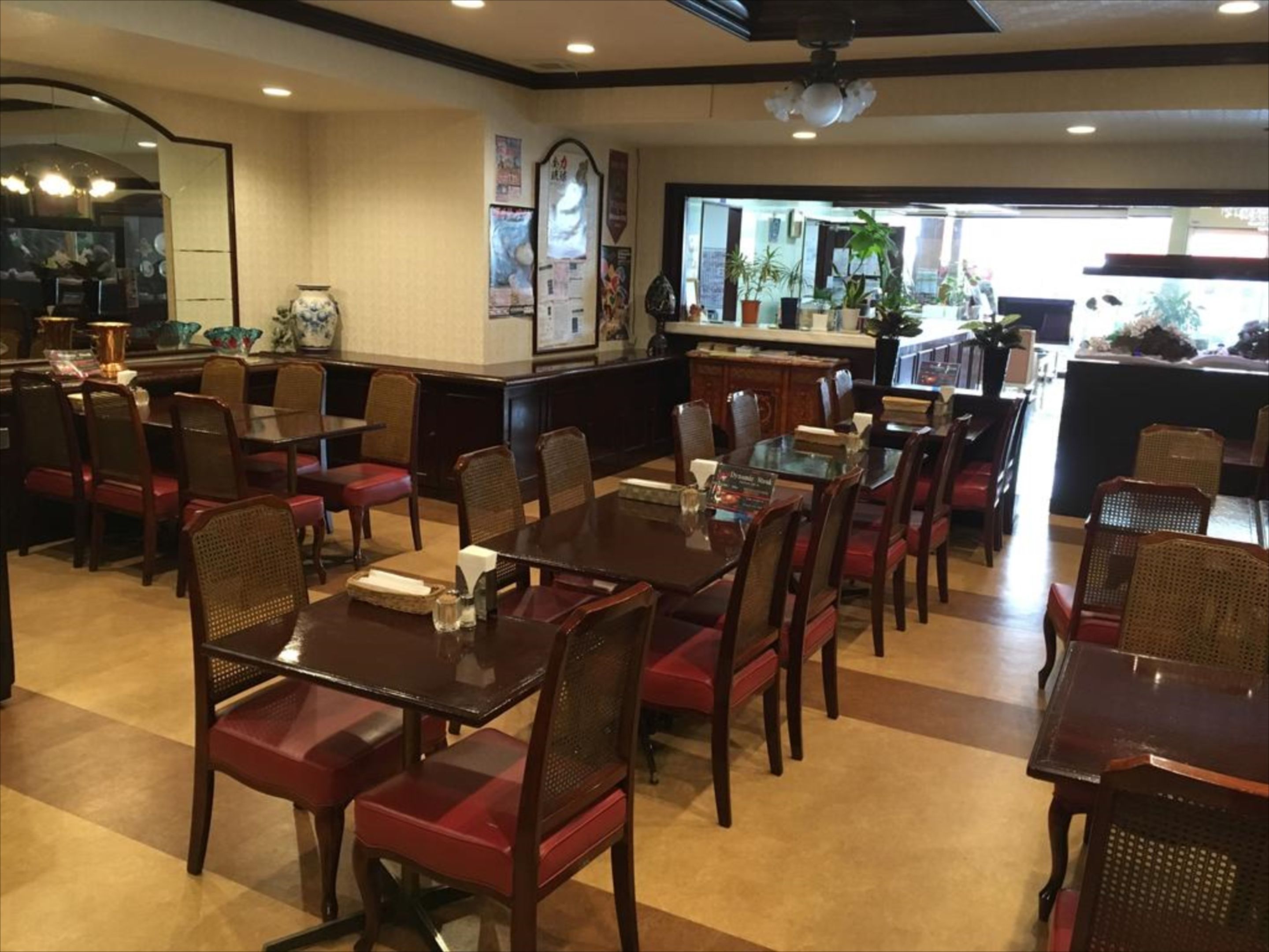 A restaurant with multiple dining tables and chairs, a bar area, and a view of the street outside.