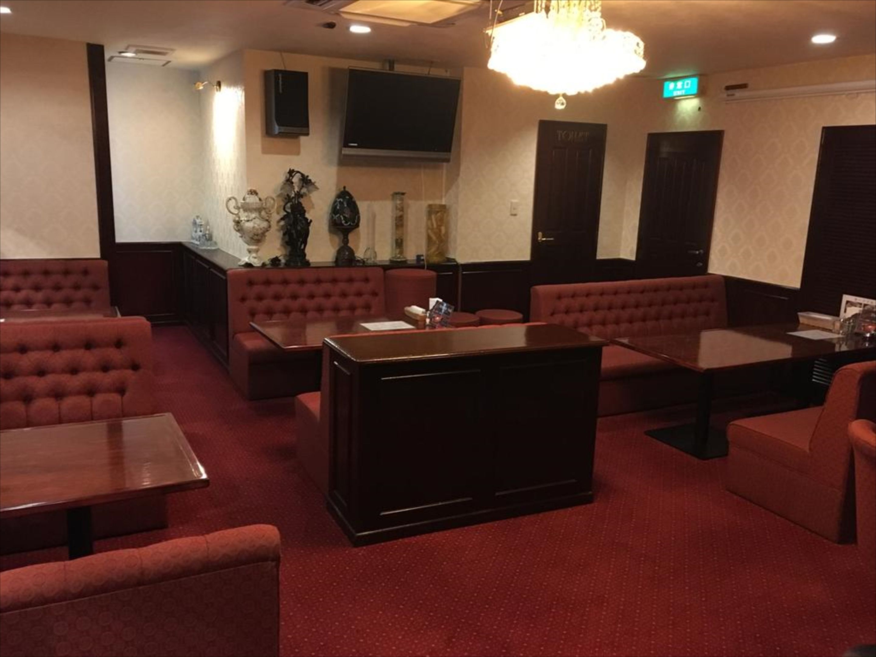 A lobby with red upholstered seating, a central coffee table, and a chandelier.