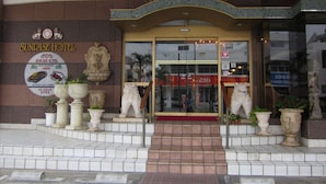 Eingang des Sunrise Hotels mit Schild, Pflanzgefäßen und einer Löwenstatue.