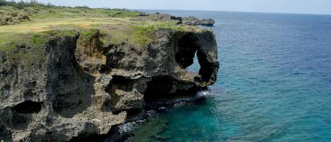 A coastal landscape with a prominent rock formation featuring a natural arch.
