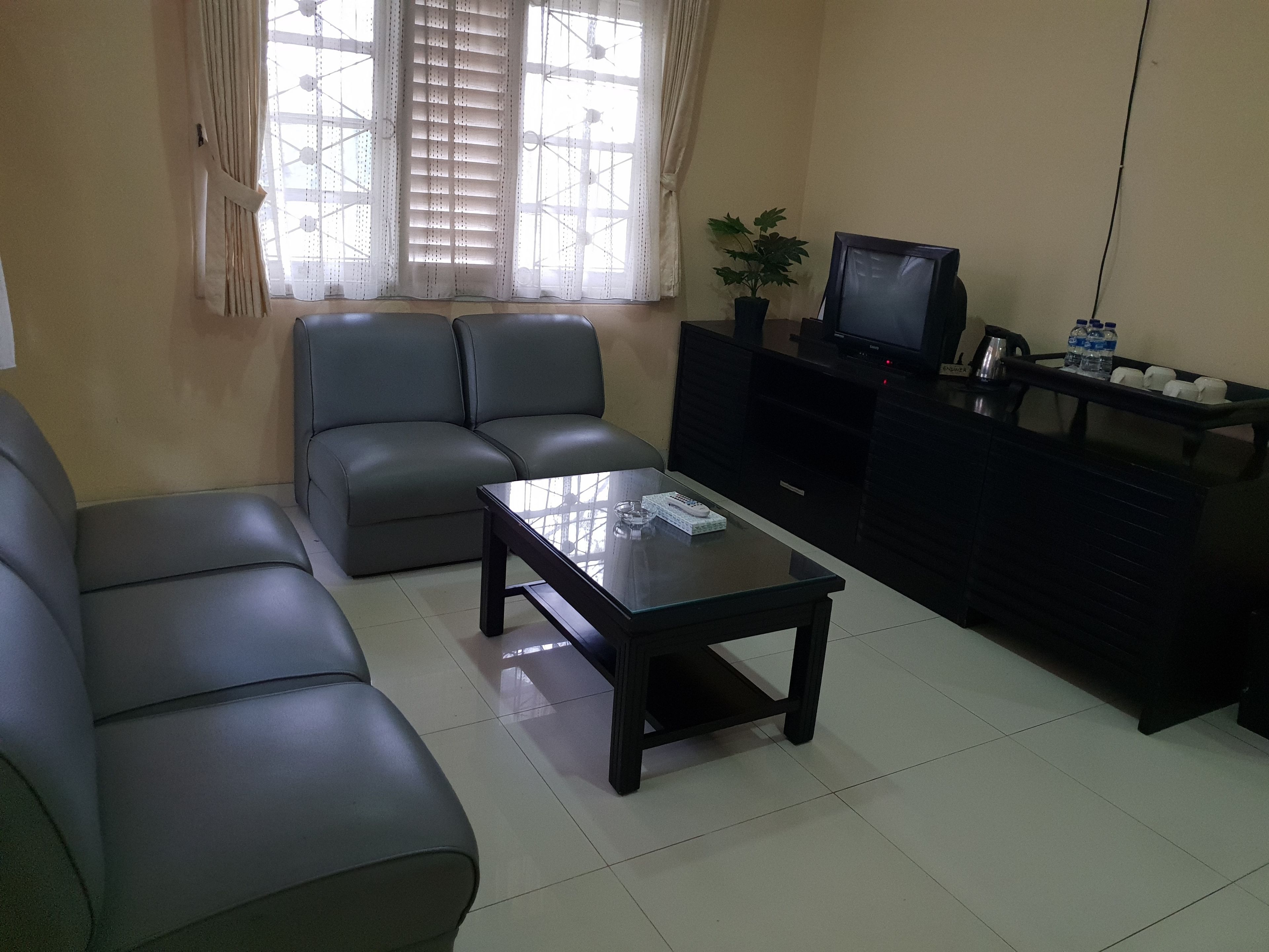 A living room with a sofa set, a coffee table, a television, and a cabinet with water bottles.