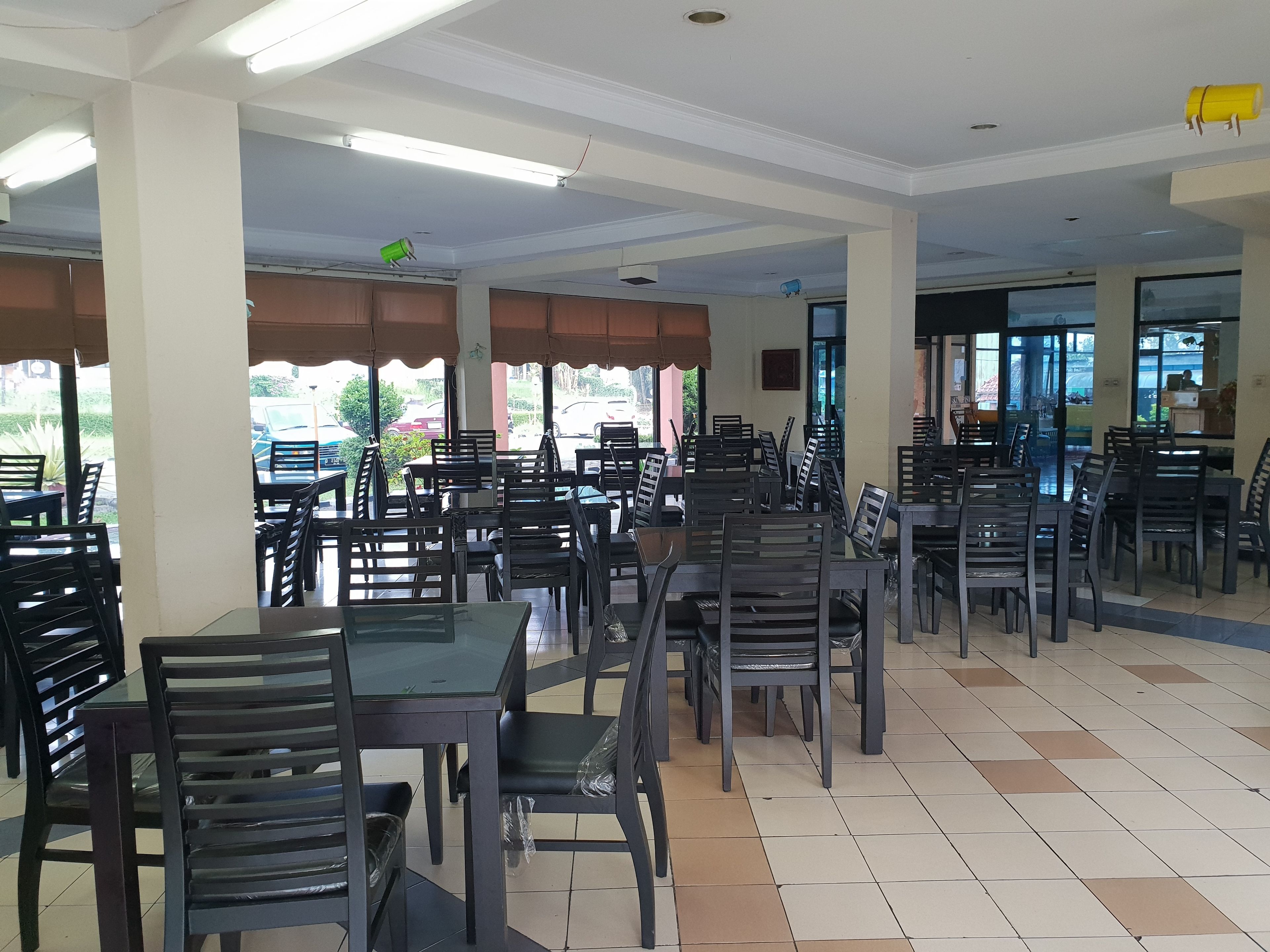 Un vaste espace de restauration intérieur, doté de nombreuses tables et chaises, de grandes fenêtres et d’un sol carrelé.
