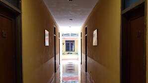 A long, narrow hallway with yellow walls and tiled flooring. - Hotel Royal Juanda (Jakarta)