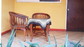 A room with a wooden chair and table, a window with blinds, and a door marked with the number 55. - Hotel Royal Juanda (Jakarta)
