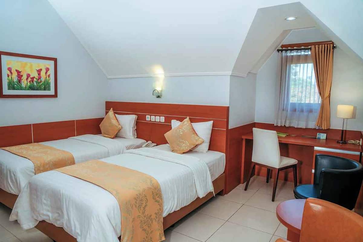 Een hotelkamer met twee bedden, een bureau en een stoel.