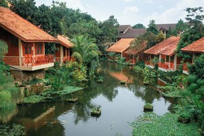 A riverside hotel with traditional architecture, wooden balconies, and lush greenery.