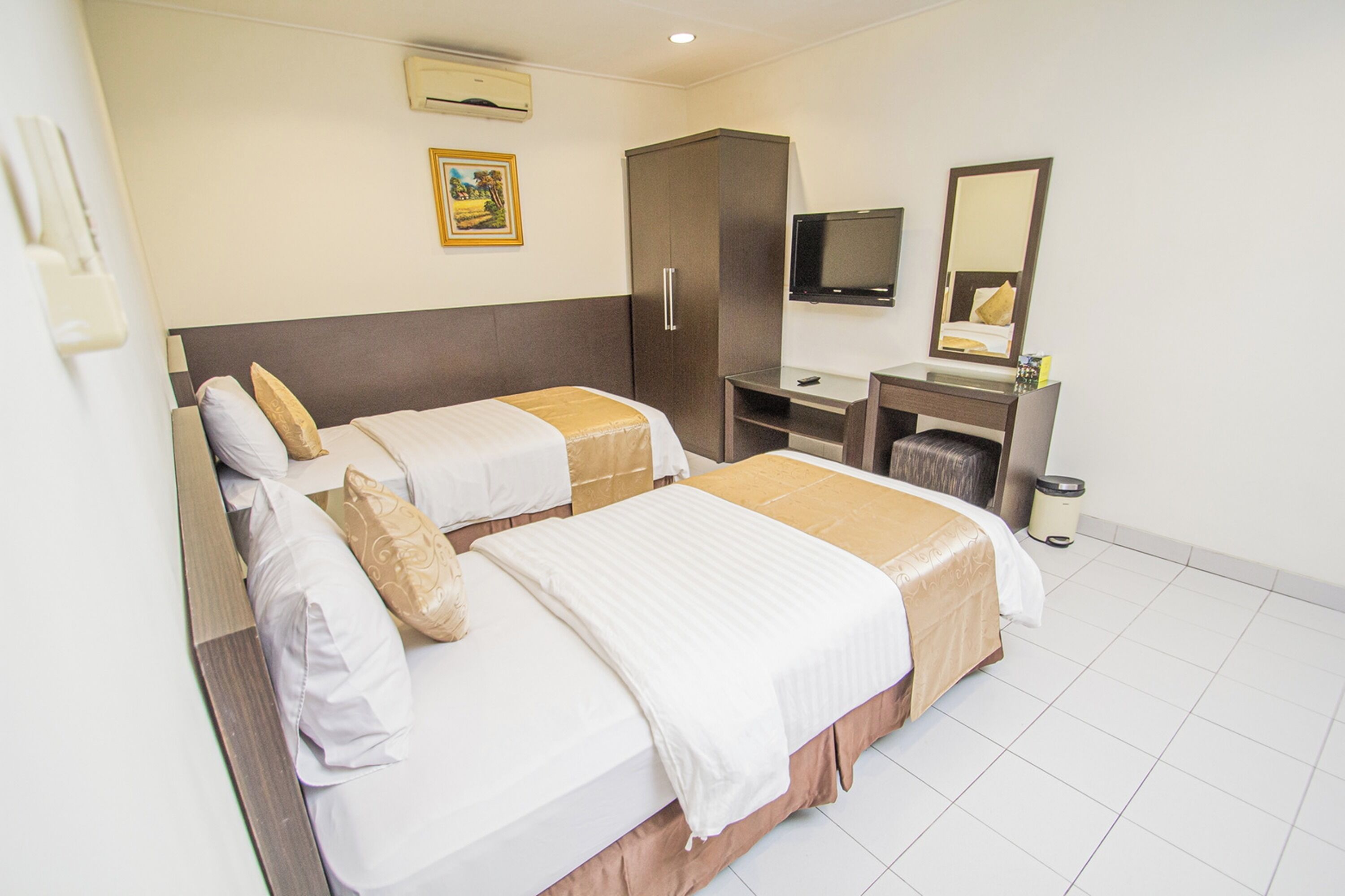 Habitación de hotel con dos camas, televisión, espejo, armario y escritorio.
