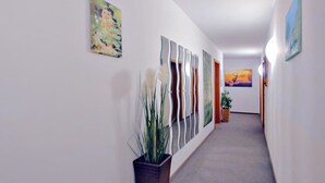 En gang med en plante, abstrakt kunst og en dør i enden.