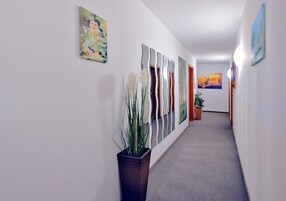 Un pasillo con una planta, arte abstracto y una puerta al final.