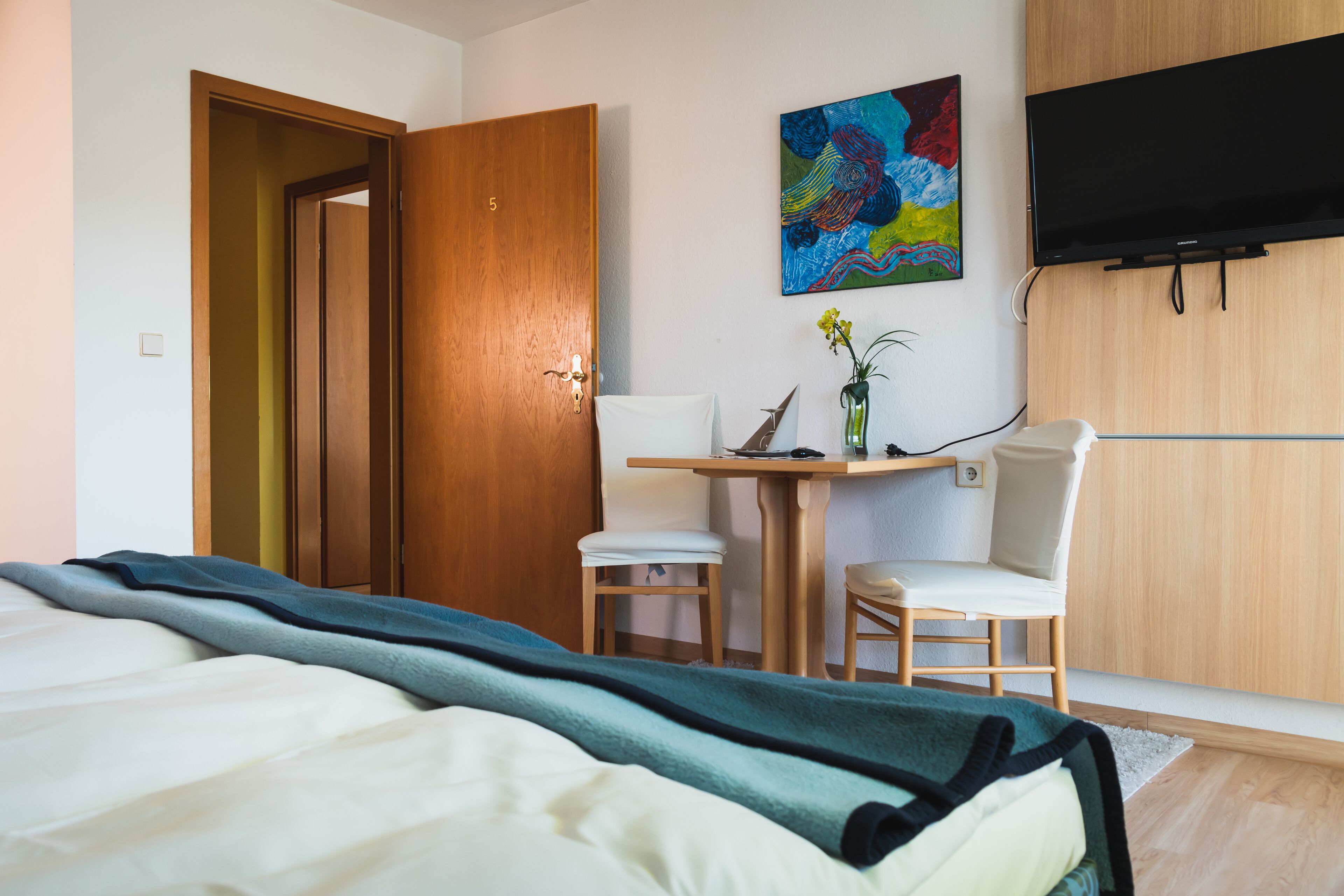 Une chambre d’hôtel avec un lit, un bureau et une chaise, une télévision et un tableau au mur.