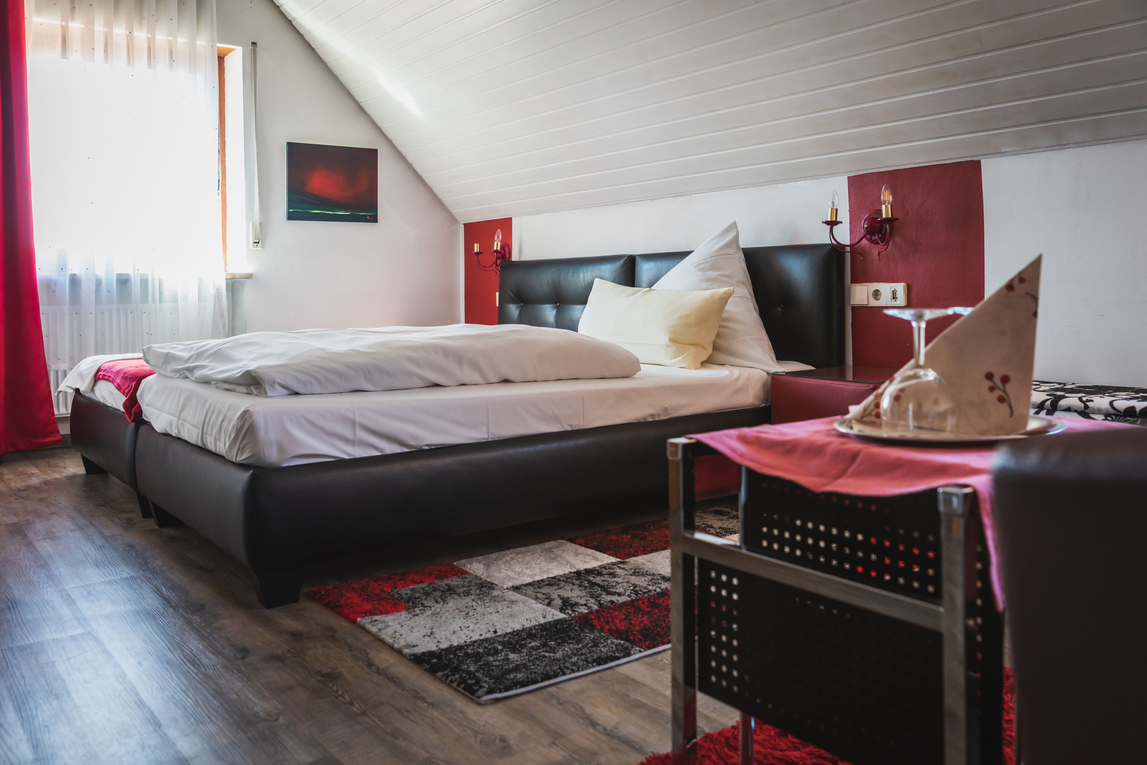Un dormitorio con cama, escritorio, silla y ventana con cortinas.