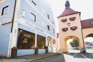 Un hotel llamado "Hotel Kattenbeck" con una entrada amplia y macetas con flores.