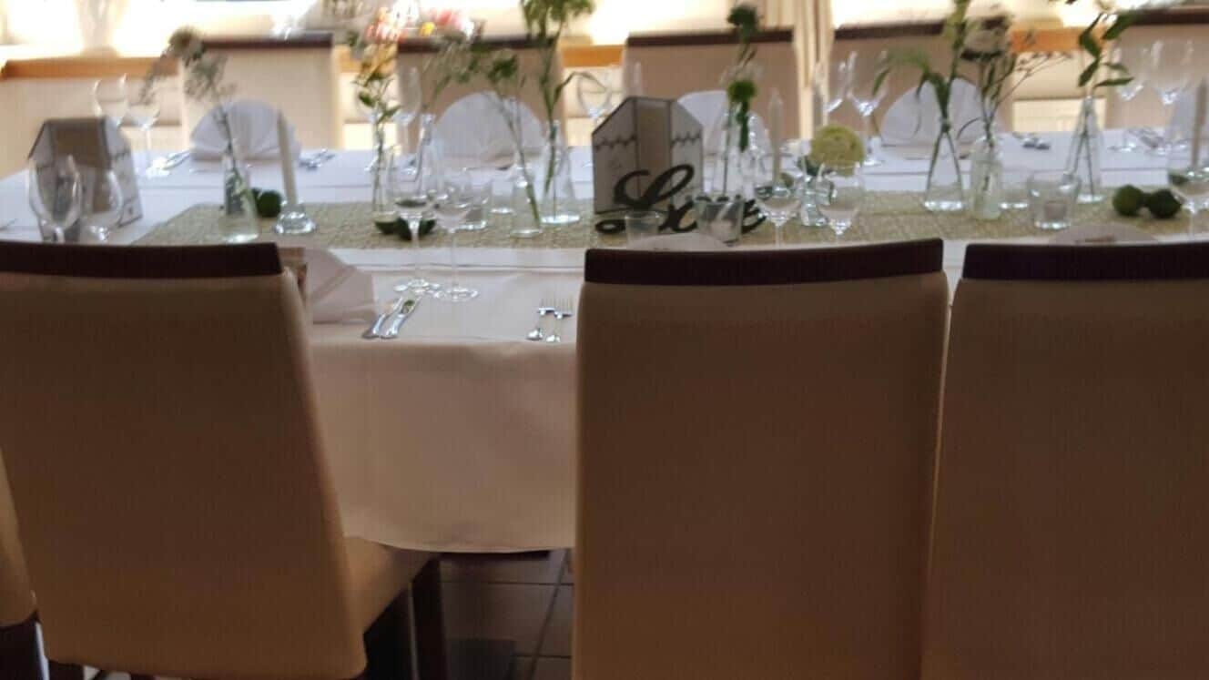 Una mesa de comedor dispuesta con cristalería, platos y un centro de mesa con un letrero que dice 'Love'.