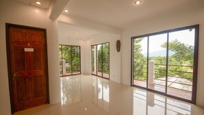 A spacious, well-lit hallway with a polished floor, large windows offering a view of greenery and mountains, and a wooden door labeled "Reception". - Hilltop Pool and Villa (Puerto Princesa)