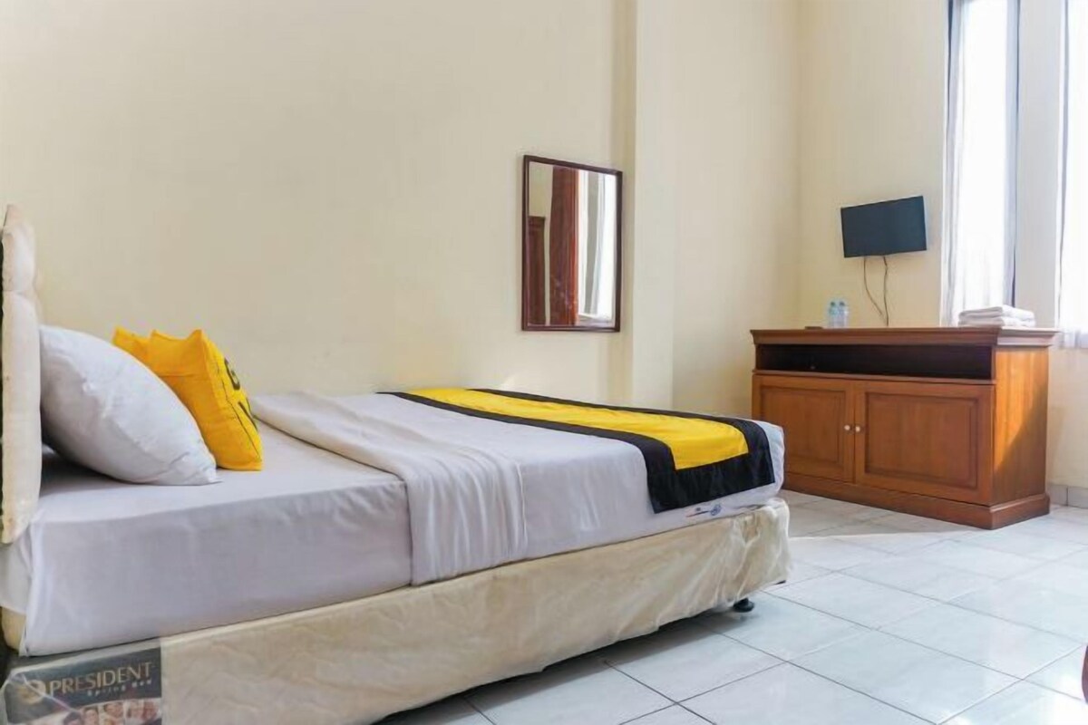 A hotel room with a bed, a wooden cabinet, a television, and a window.