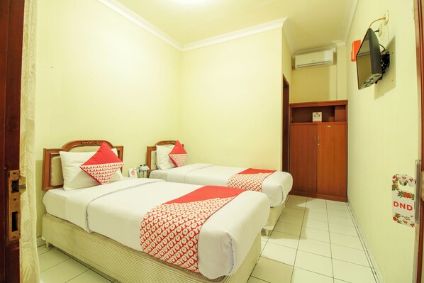 A hotel room with two beds, a wooden wardrobe, a television mounted on the wall, and a sign with 'DND' on the door. - Hotel Astria Graha (Bandung)