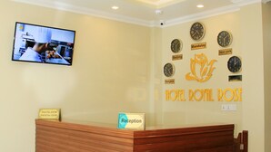 Una mesa de recepción con un letrero que indica "Reception" y un reloj de pared que muestra "Mandalay" y "New York".