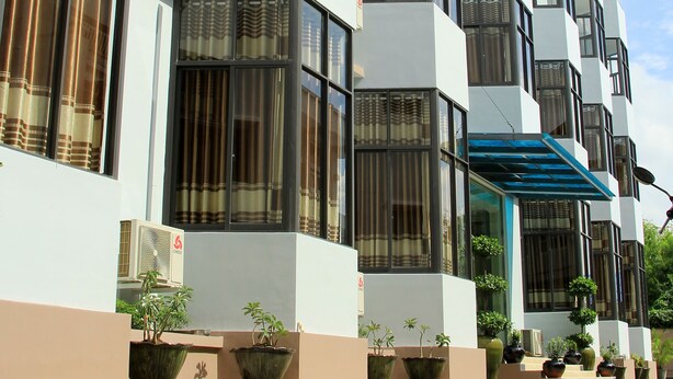 Un edificio moderno con varios balcones, ventanas amplias y plantas en macetas.