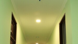 Un pasillo con pared verde claro, molduras oscuras y una puerta de madera al final.