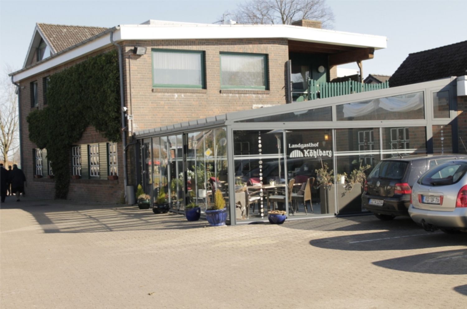 A building with a glass storefront, a brick facade, and a green roof.