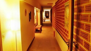 Un pasillo de hotel con un banco de madera, un reloj y una puerta con diseño decorativo.