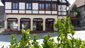 A traditional half-timbered building with multiple storefronts, including signs for 'Qualität & Frische' and 'Metzgerei'. - Hotel Krone (Deckenpfronn)