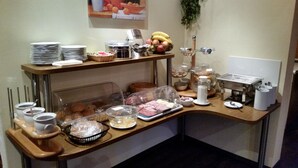A buffet setup with various food items and serving utensils. - Hotel Krone (Deckenpfronn)