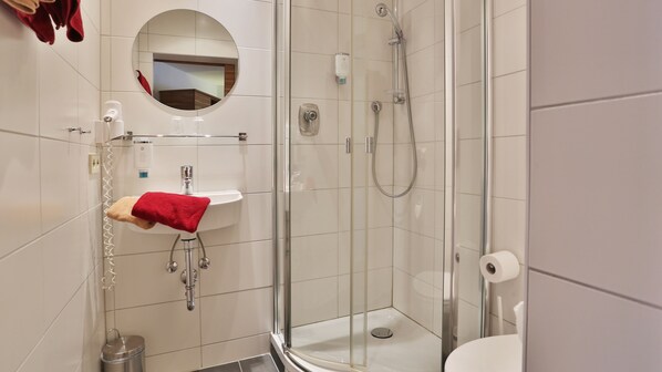 A modern bathroom with a glass-enclosed shower, a white sink, and a mirror above it. - Hotel Krone (Deckenpfronn)