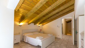 A bedroom with a wooden ceiling, a bed, a nightstand, and a dresser. - Villa Arenella con Piscina by Wonderful Italy (Syracuse)