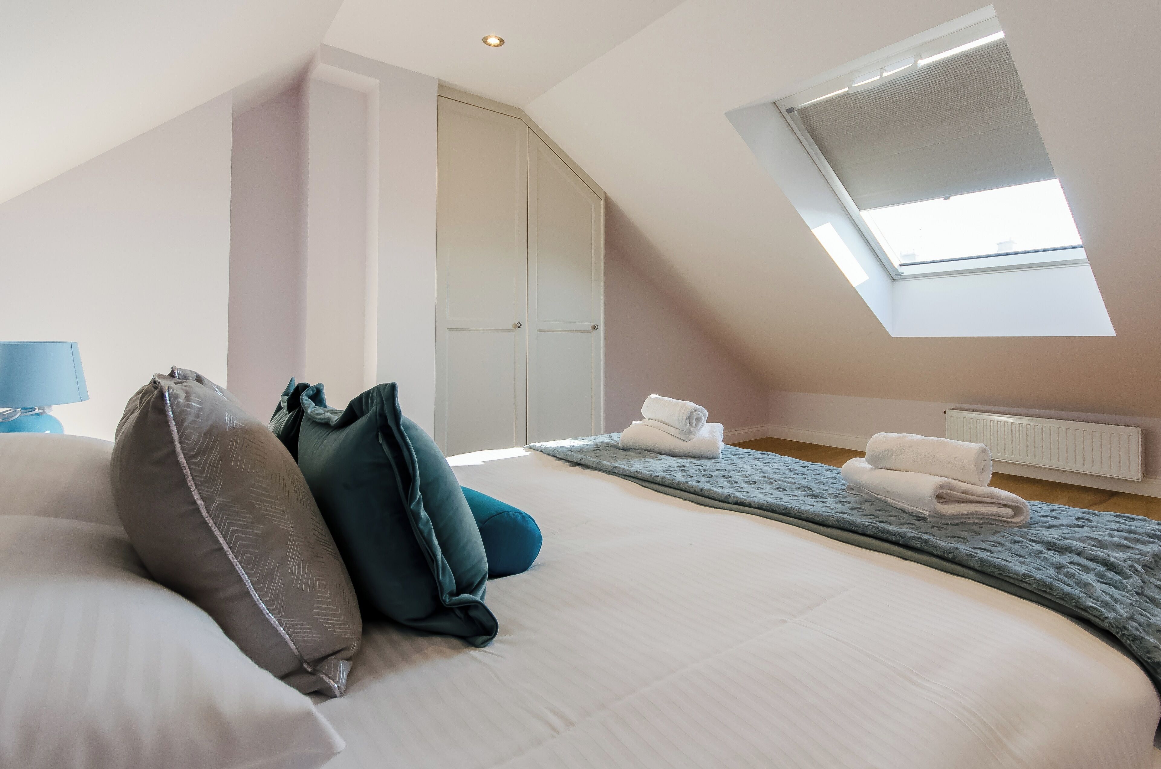 Ein Schlafzimmer mit einem großen Bett, einem Oberlicht, einer Heizung und einem Kleiderschrank.