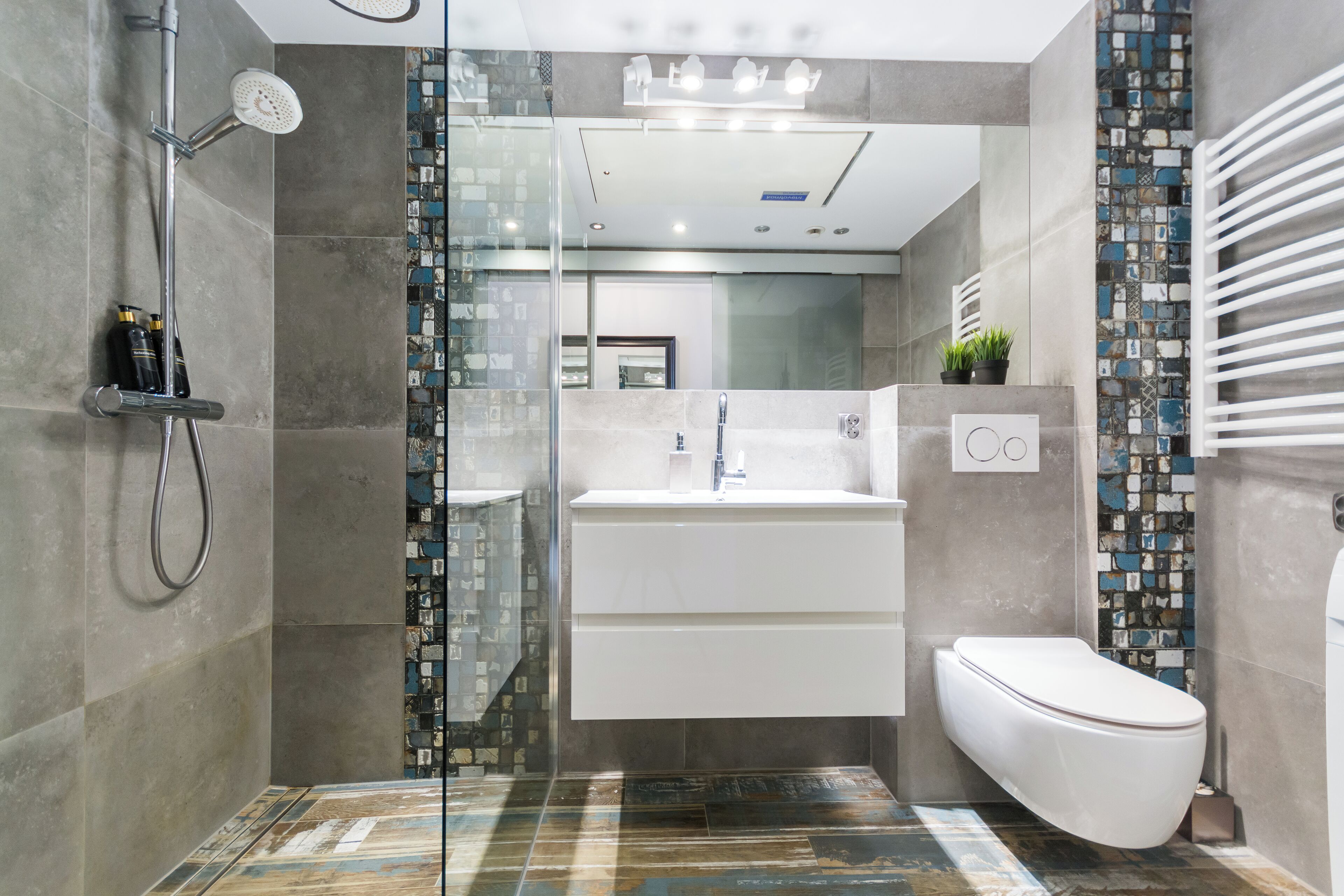 Een moderne badkamer met een douchecabine van glas, een wit wastafelmeubel en een toilet.