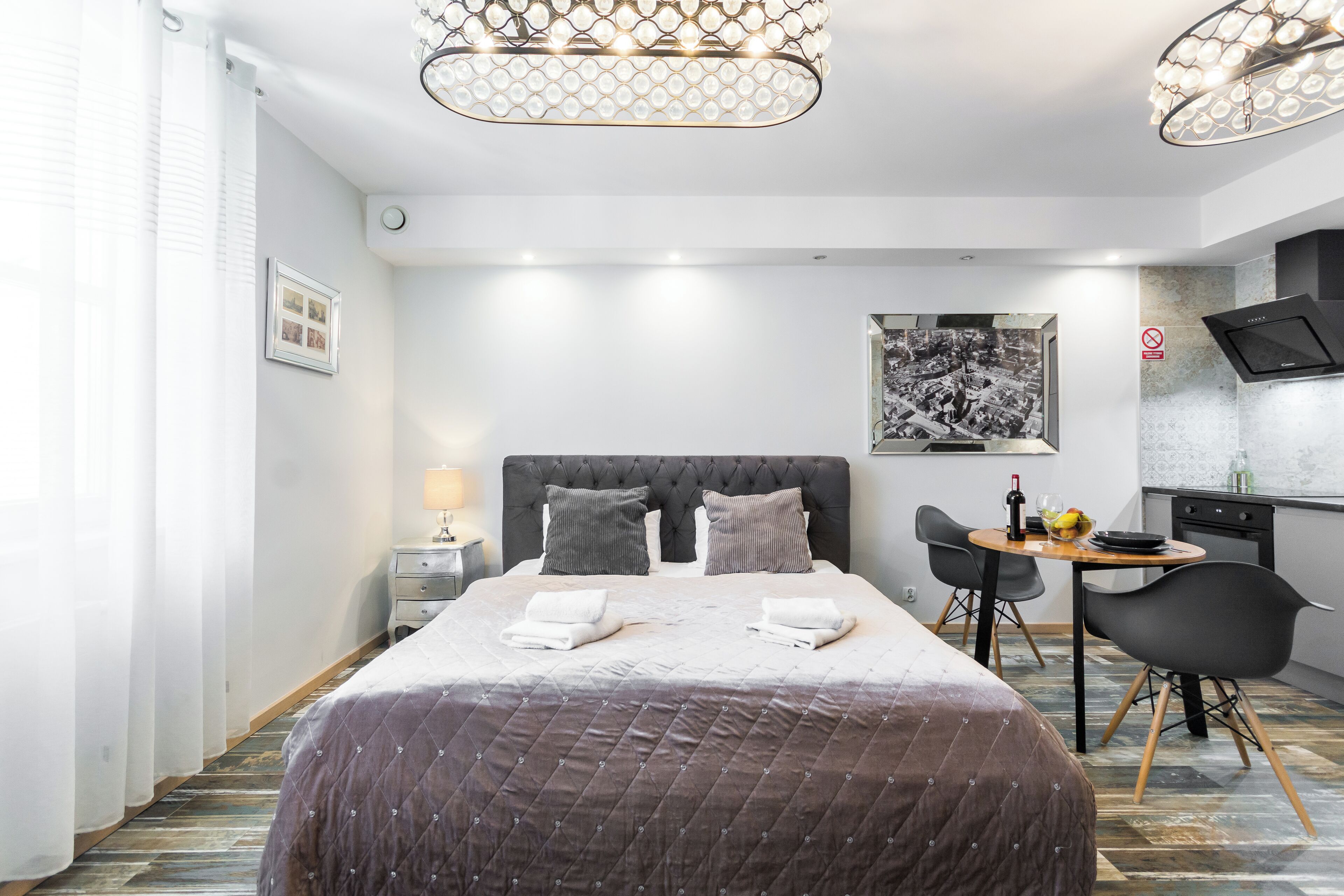 Moderni hotellihuone, jossa on siististi pedattu sänky, ruokailutila ja keittiö.