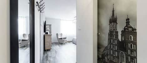 A hallway with a wooden floor, a coat rack, and a framed picture of a building.