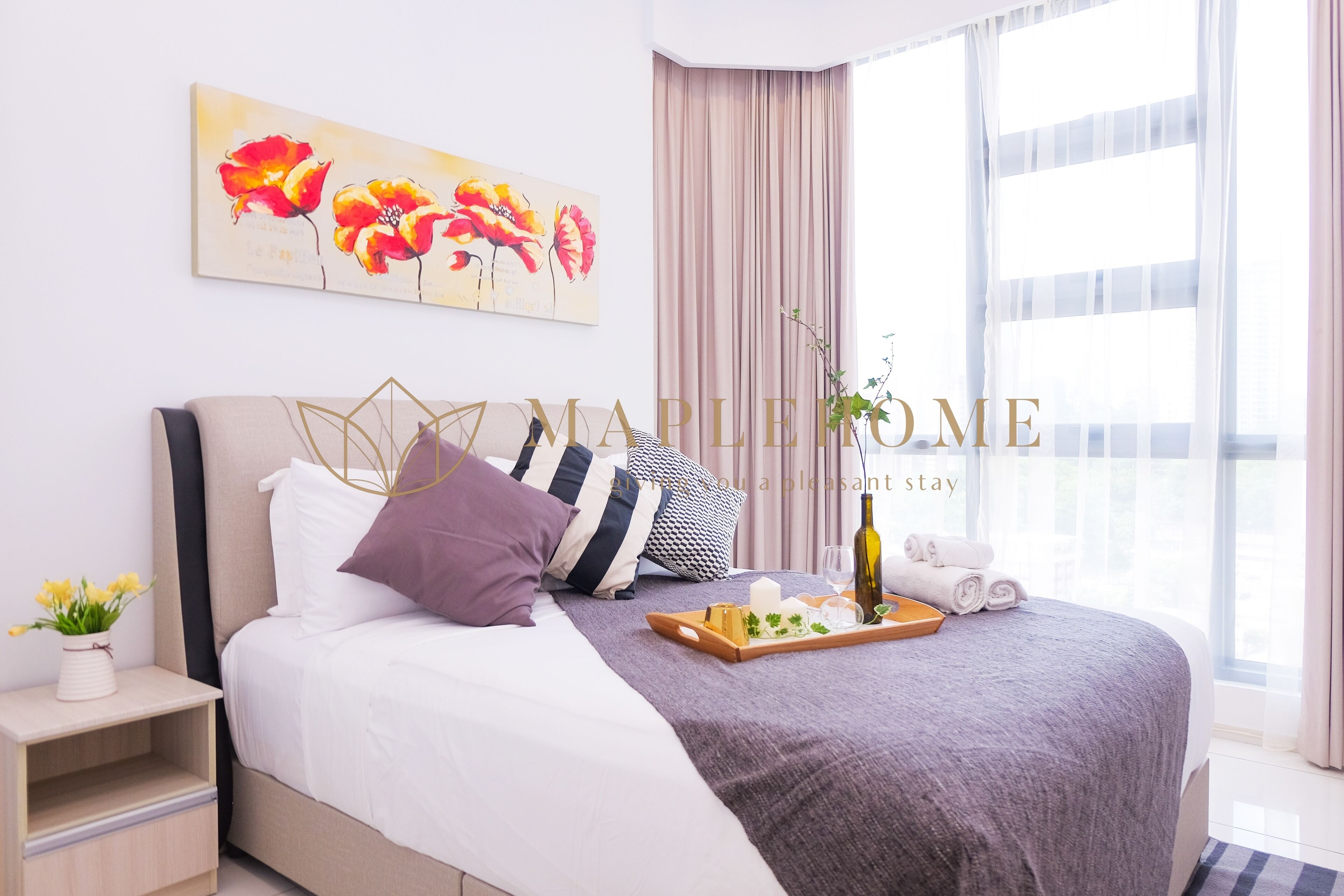 Una habitación de hotel con una cama, una bandeja de aperitivos, una botella y un jarrón de flores.