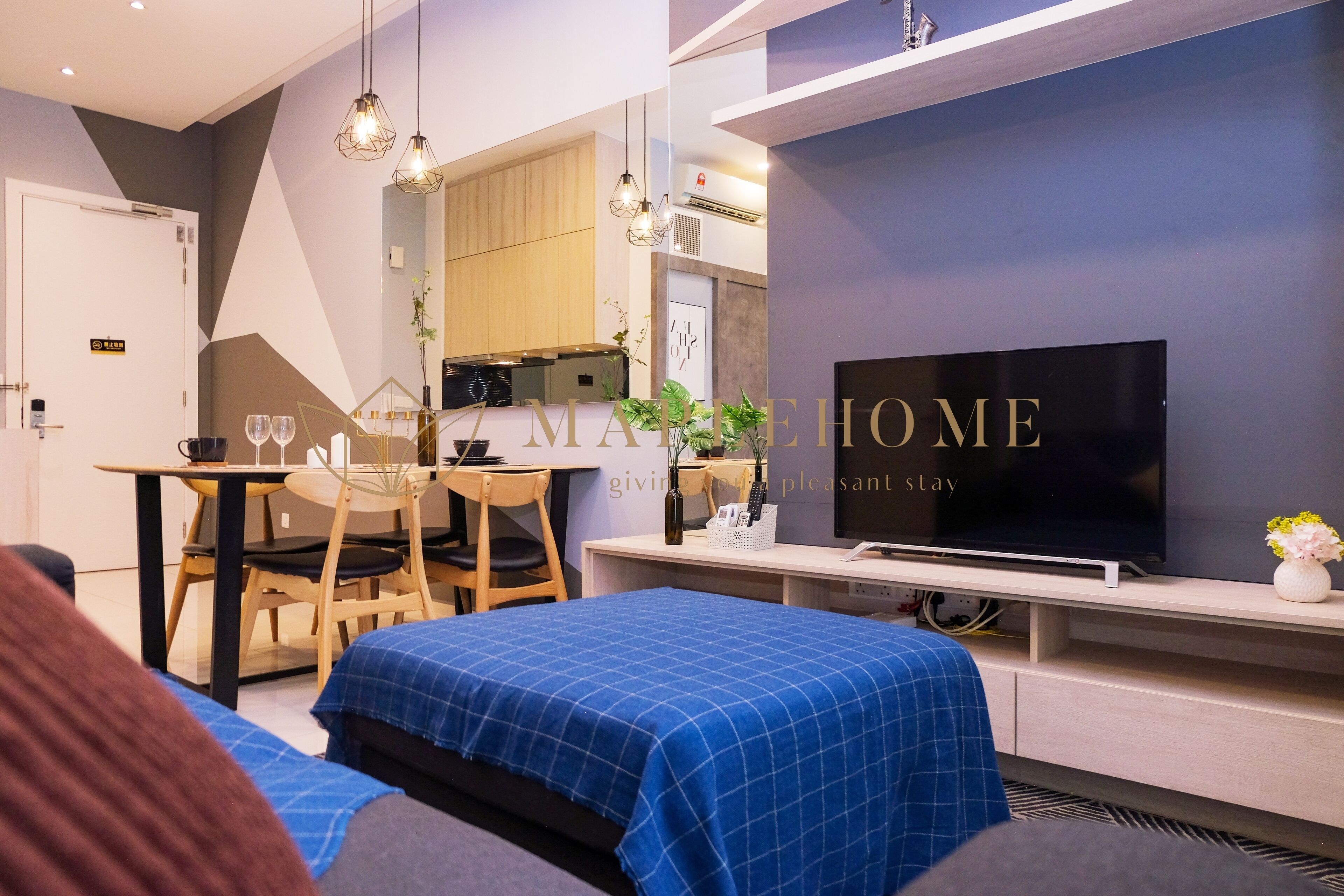 A modern hotel room with a bed, a TV, a desk, and a dining area.