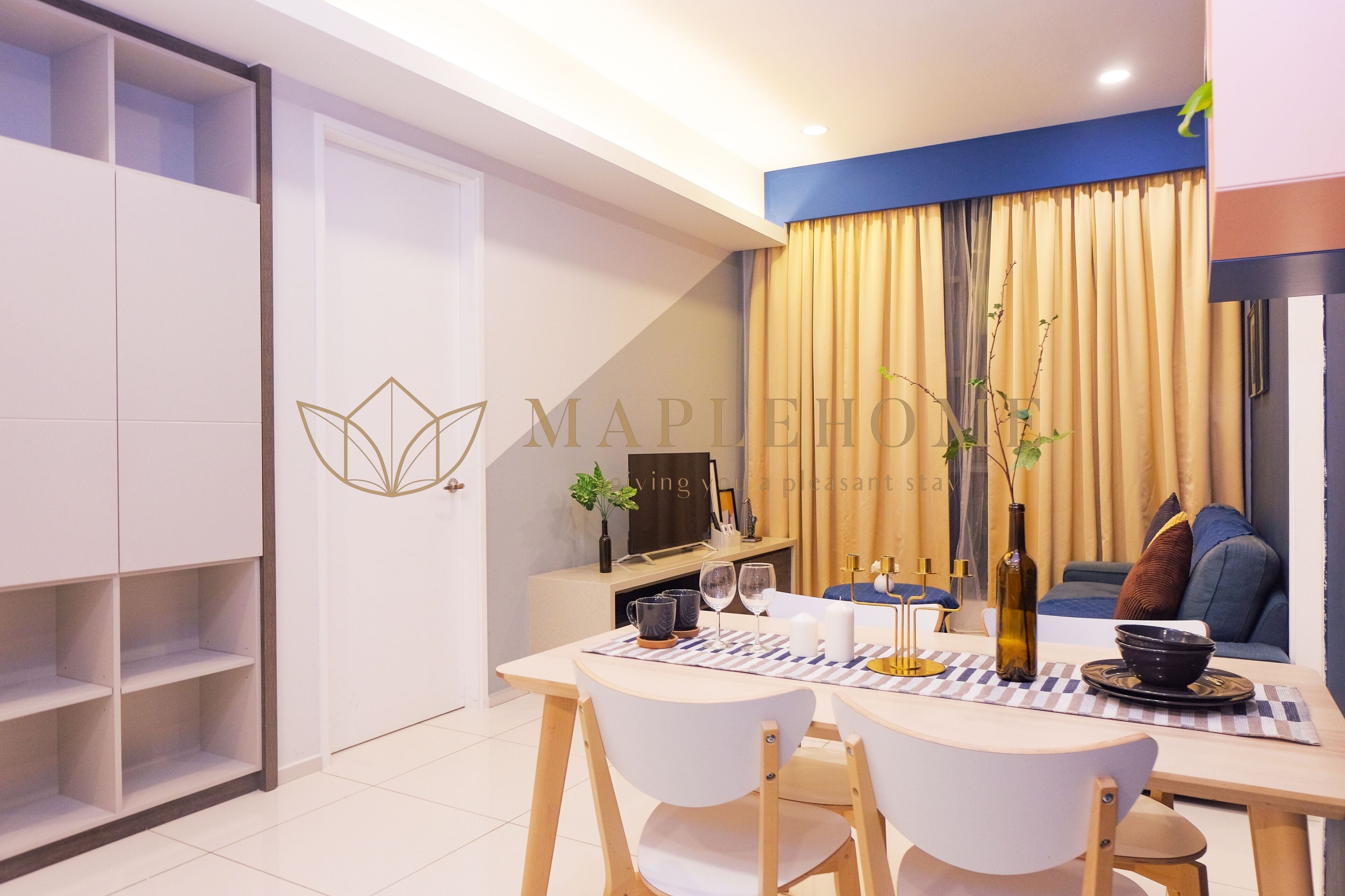 A modern dining area with a table set for two, a sofa, and a bookshelf.
