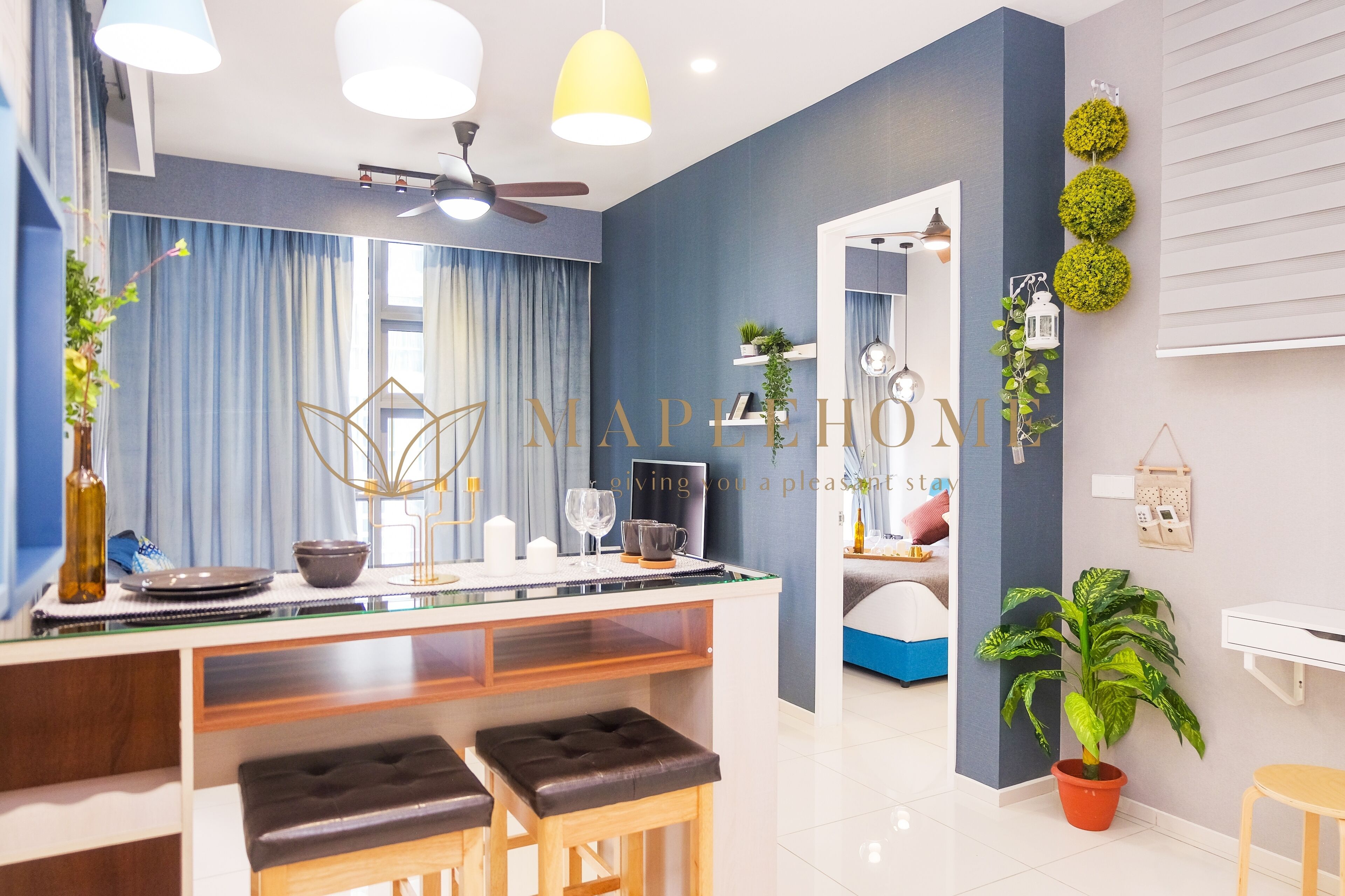 A modern kitchen with a bar area, a ceiling fan, and a dining space with stools.