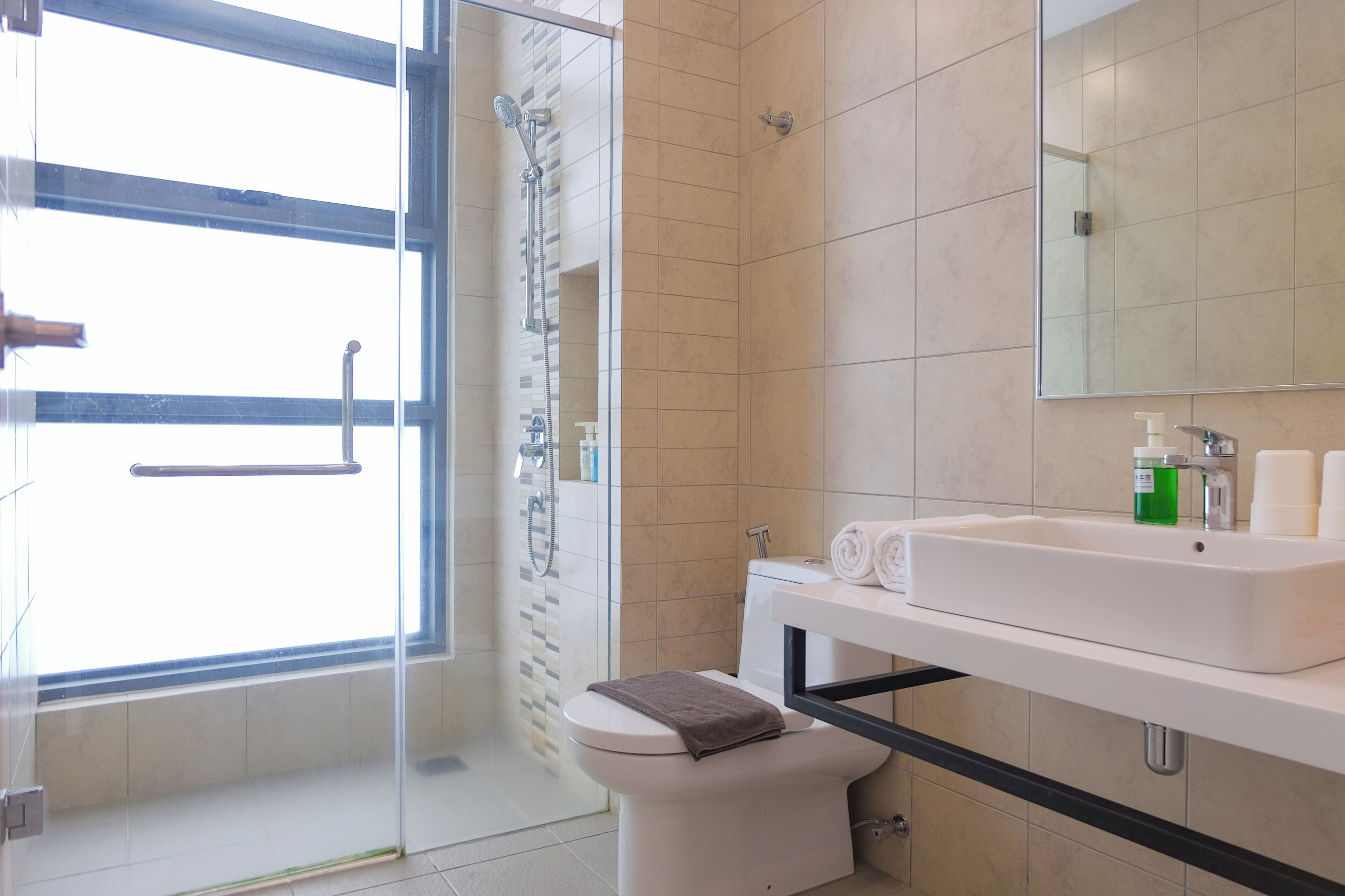 A modern bathroom with a glass shower enclosure, a white toilet, and a sink with toiletries.