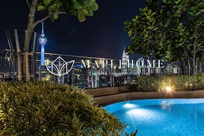 A pool area with a city skyline in the background, including a prominent tower.