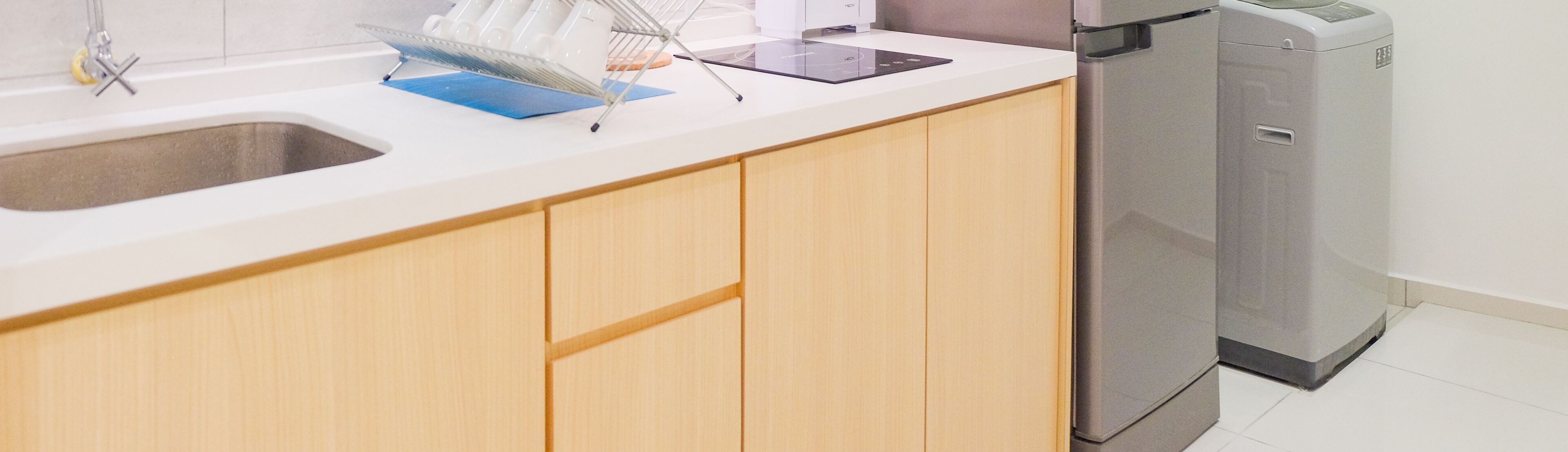 A kitchen with a sink, a dish rack, a countertop, and a dishwasher.