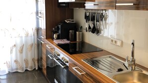 A modern kitchen with a stainless steel sink, wooden countertop, and black cabinetry. - City Apartments Will (Emmerich)