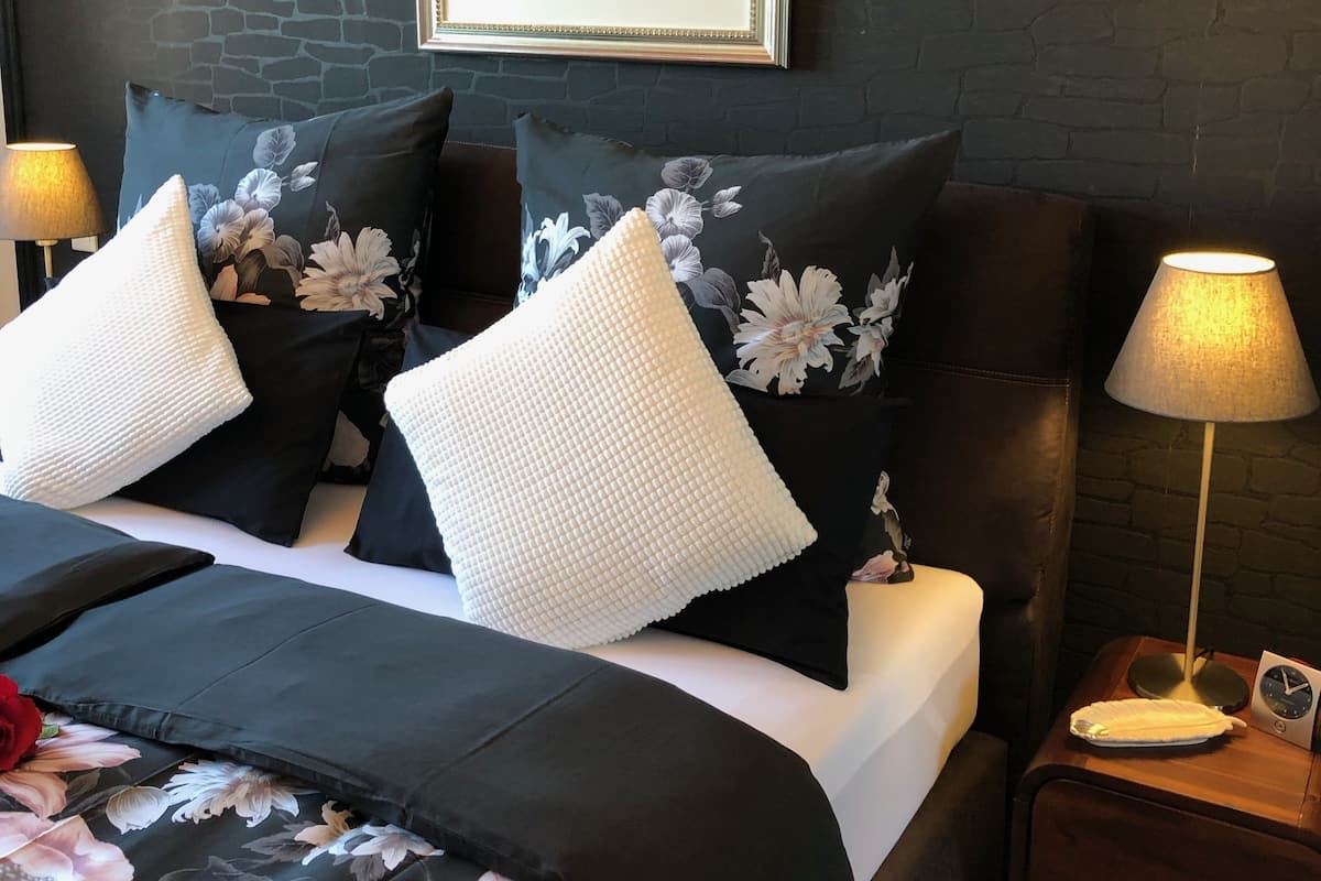 A hotel room with a bed, two nightstands, a lamp, a framed painting, and a floral bedspread.