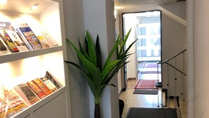 A hallway with a bookshelf, a potted plant, a carpeted area, and a staircase leading to another room. - City Apartments Will (Emmerich)